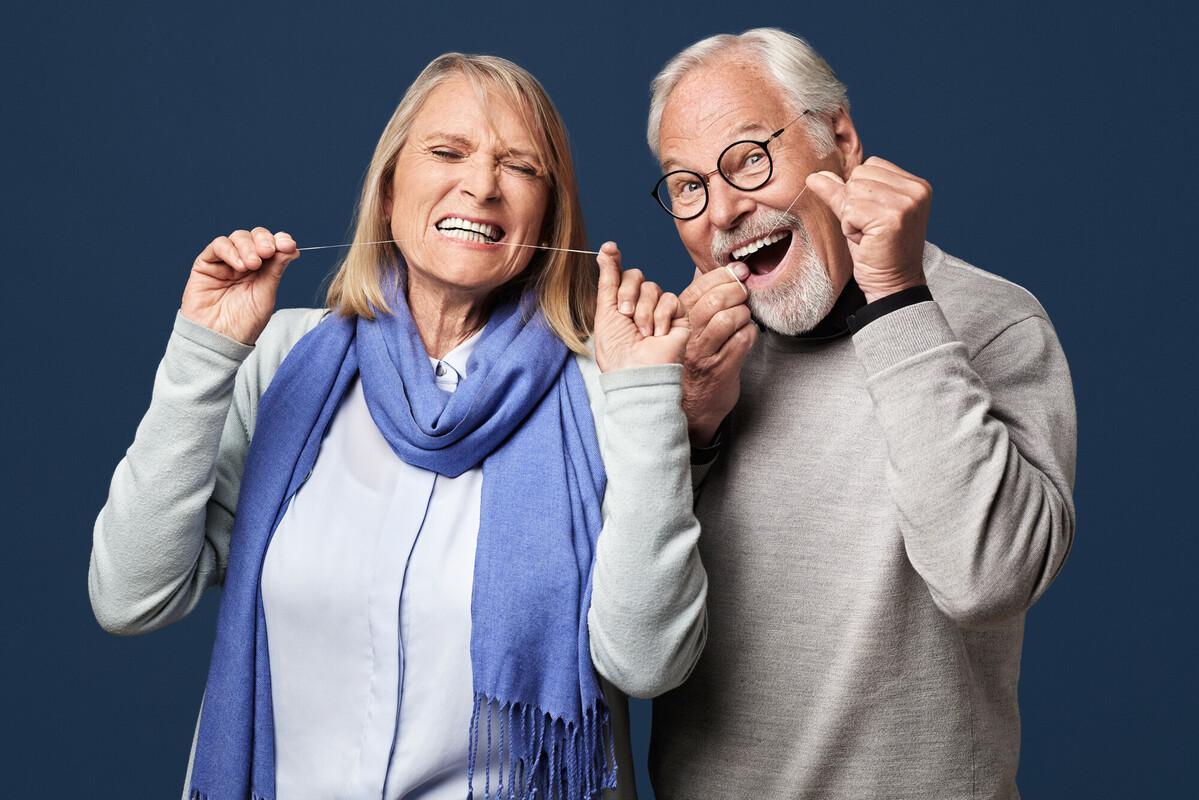 mann og kvinne rengjør tennene med tanntråd