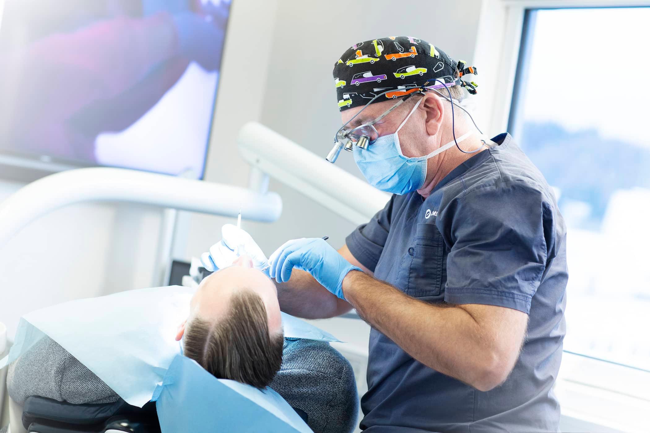 Tannlege Paul Arne Hordvik jobber med å gi Anders i tannlegestolen nye tenner.