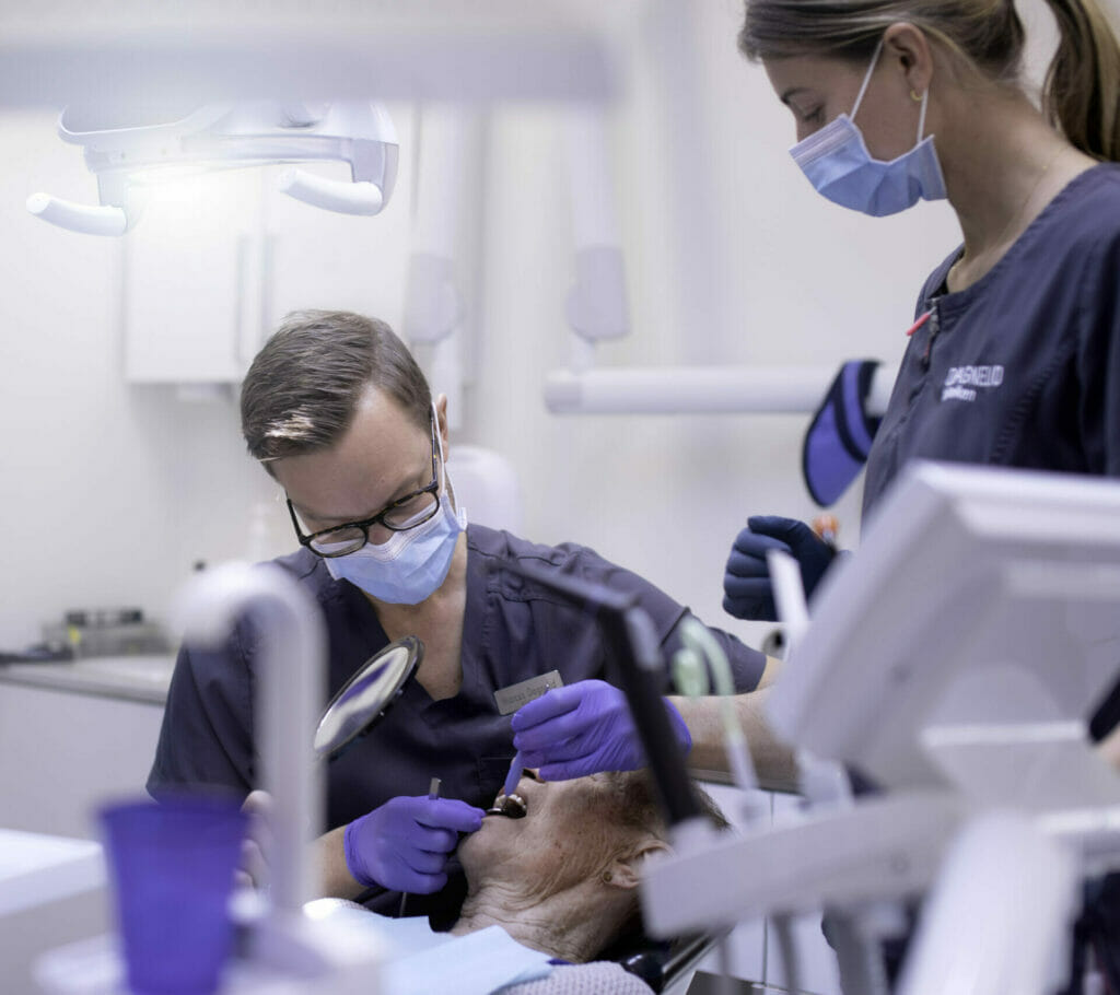 Tannlege ved Oris Dental utfører tannundersøkelse på en eldre pasient i tannlegestolen.