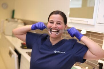 Tannbehandler viser frem stor og bredt smil med utstyr som åpner munnen.